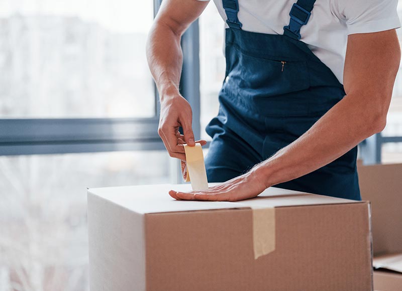 un déménageur qui ferme un carton